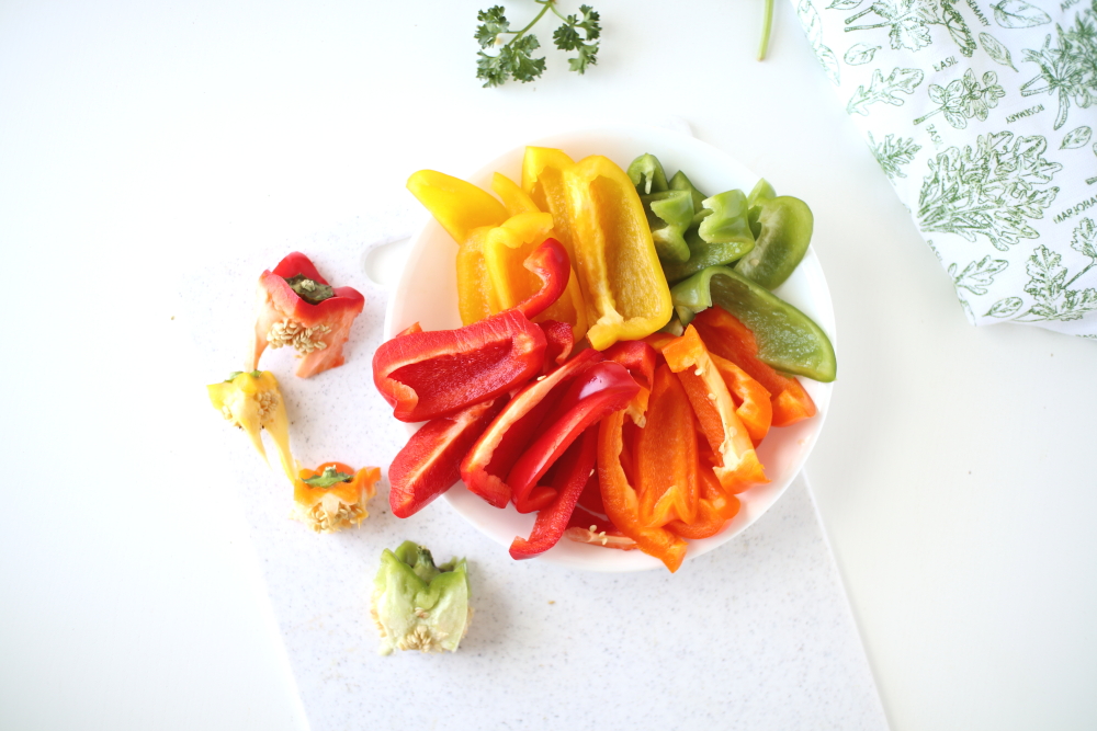 colorful sliced bell peppers on white bowl and table