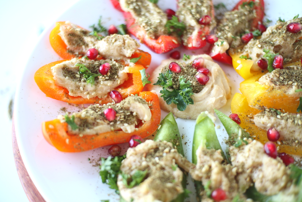 bell peppers and za'atar spiced hummus on white plate close up