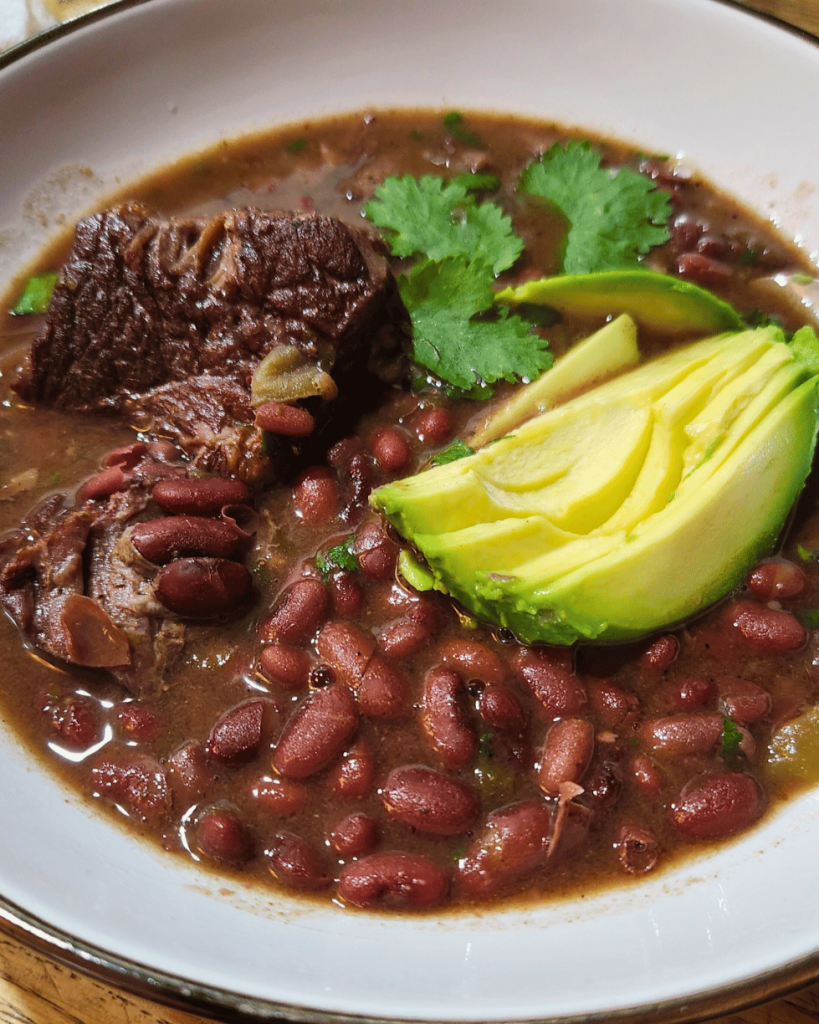 close up of honduran bean soup with beef short ribs and avocado